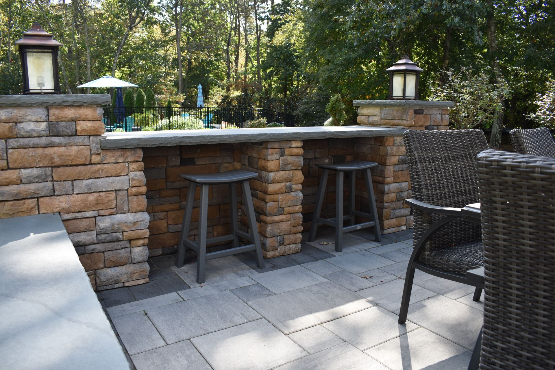 A patio with a brick wall , stools , chairs and a table.