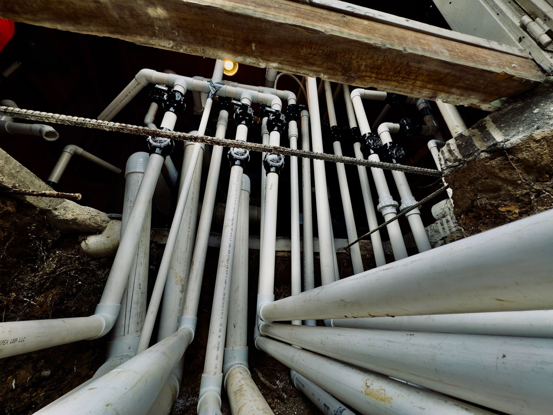 A bunch of white pipes are laying in the dirt.