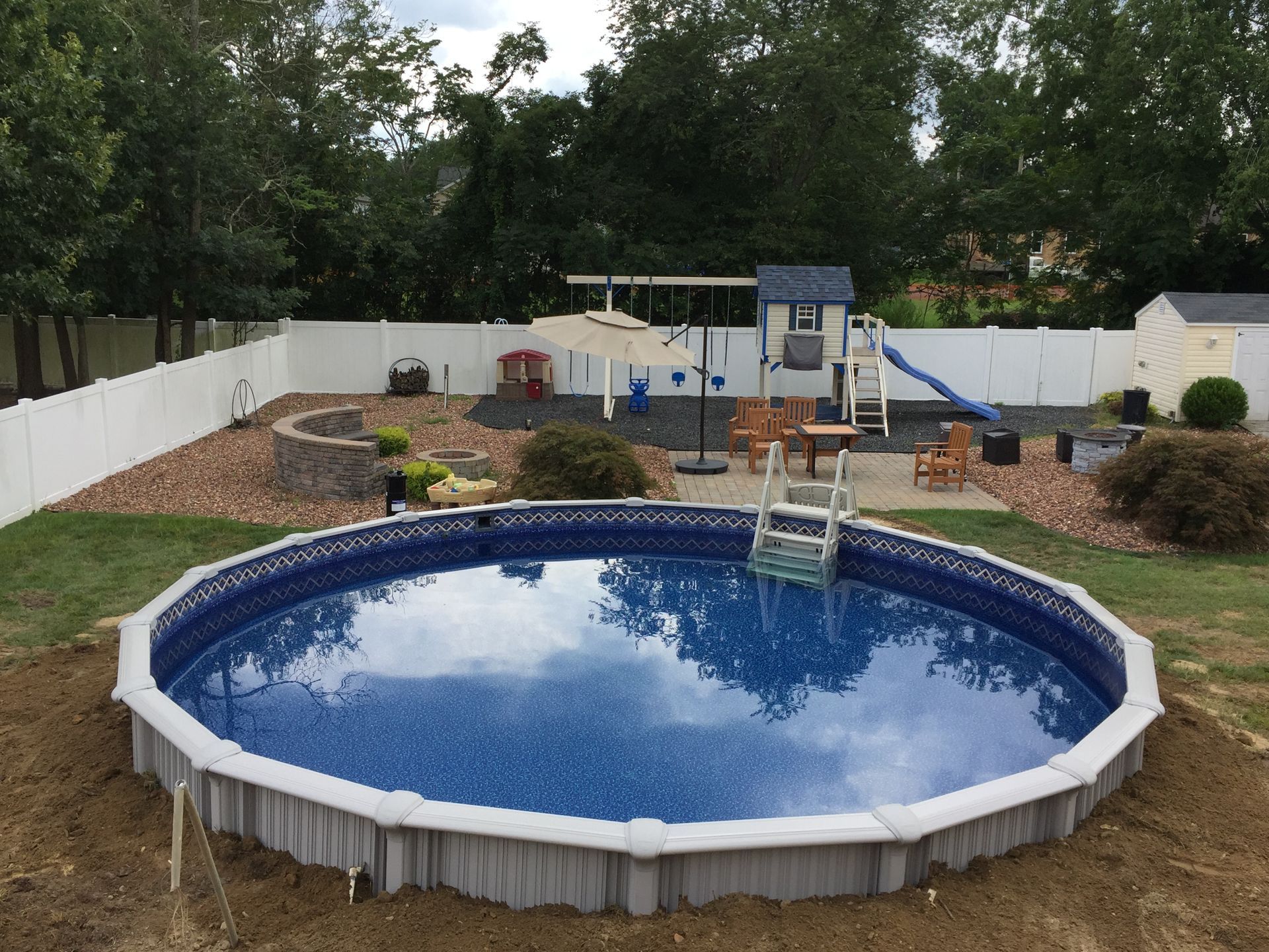 A large swimming pool in a backyard with a playground in the background.