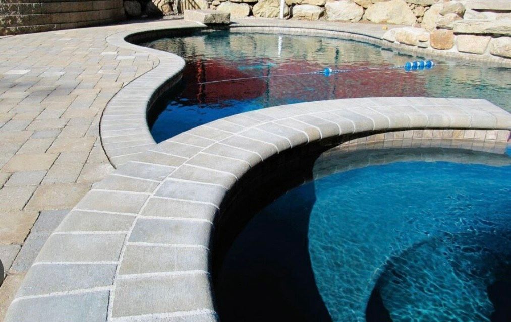 A swimming pool with a hot tub in the middle of it