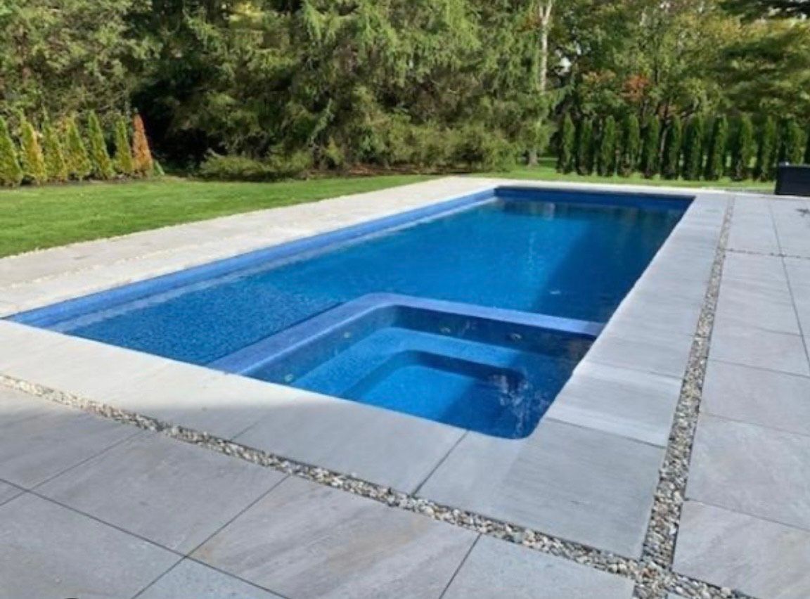 A large swimming pool with a hot tub in the middle of it.