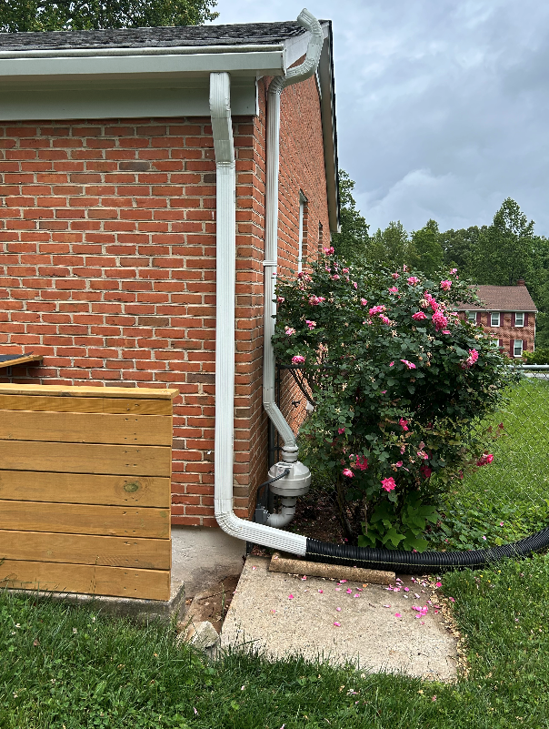 A drainpipe is attached to the side of a brick house.