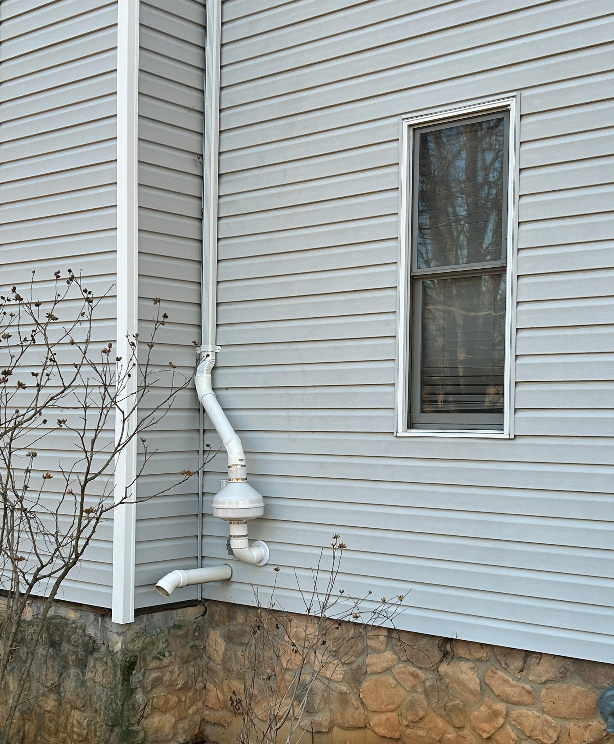 A white house with a window and a white pipe on the side