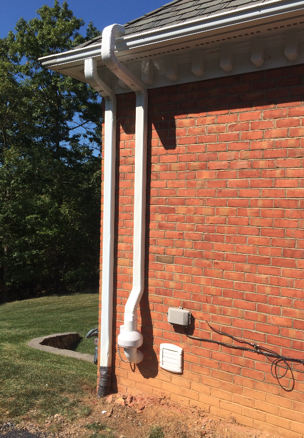 A brick house with a white gutter on the side of it.