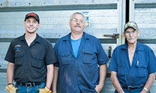 three men are standing next to each other in front of a truck .