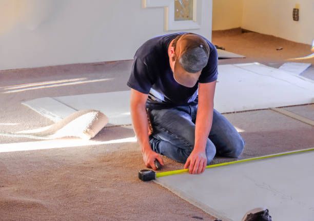 A man is measuring a piece of carpet with a tape measure.