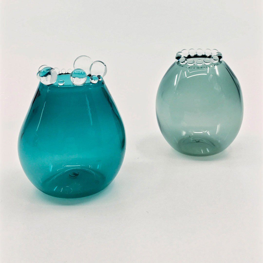 two small glass vessels, one blue and one green