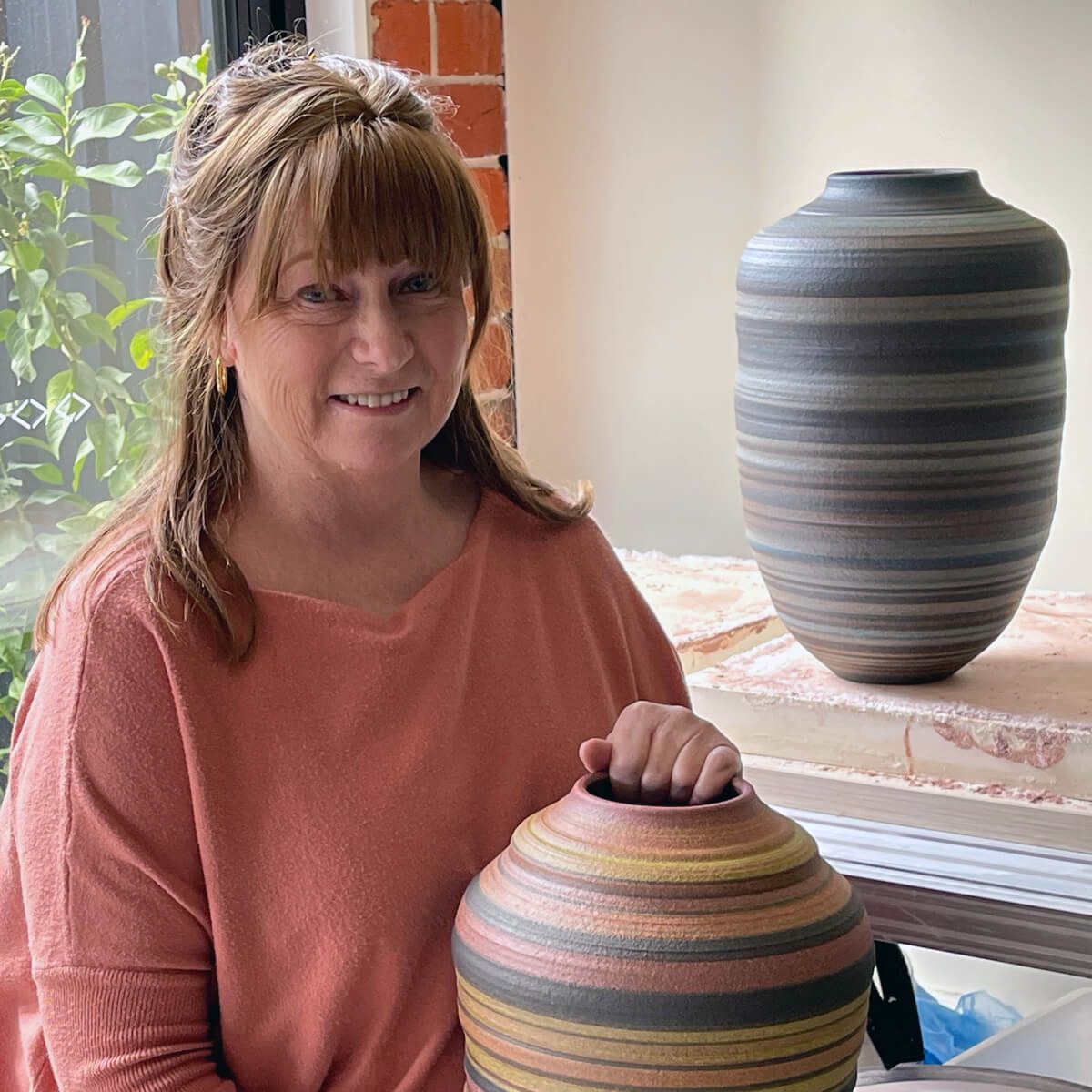 Gillian Martin holds a large, colourfully striped ceramic vessel