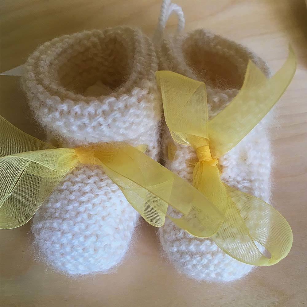a pair of cream woollen baby booties, made by Jo Cargil
