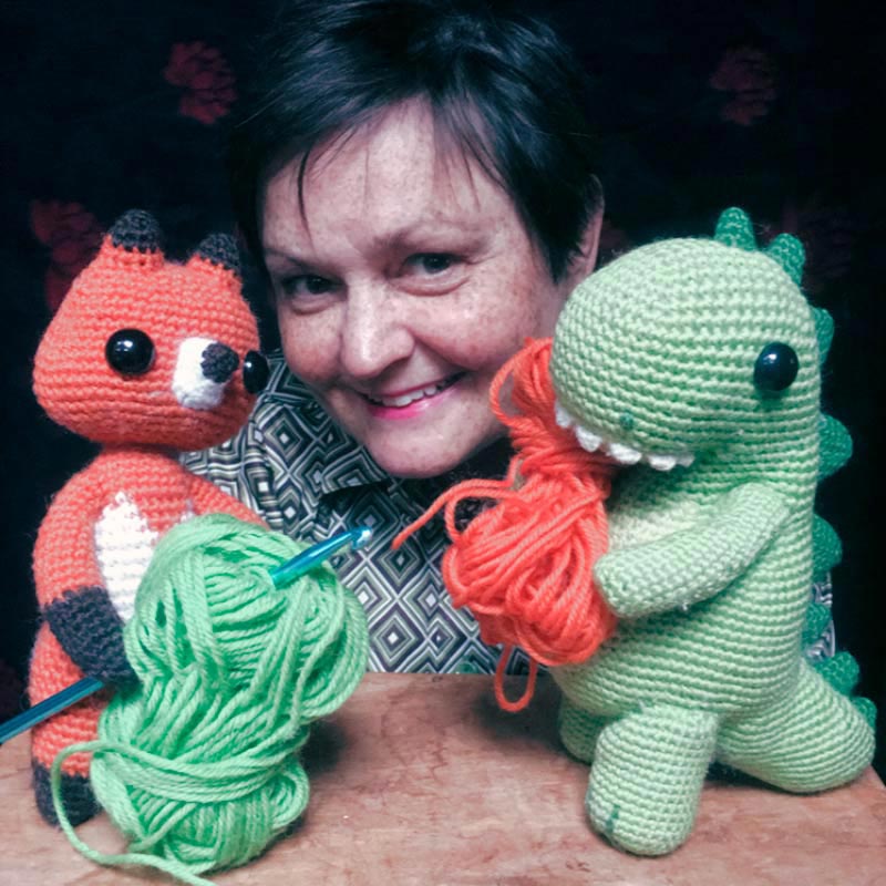 Julie Ramsden poses with two of her soft-sculpture animals, a red fox and a green dinosaur
