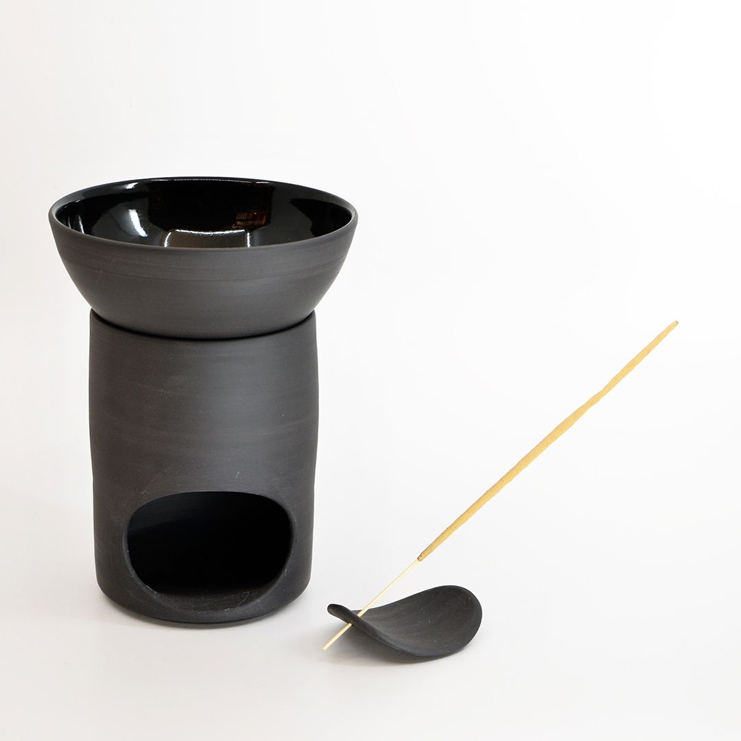 A black ceramic incense burner and a yellow incense stick