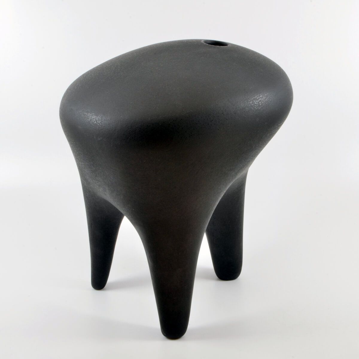 a black sculptural ceramic vase with three 'legs'