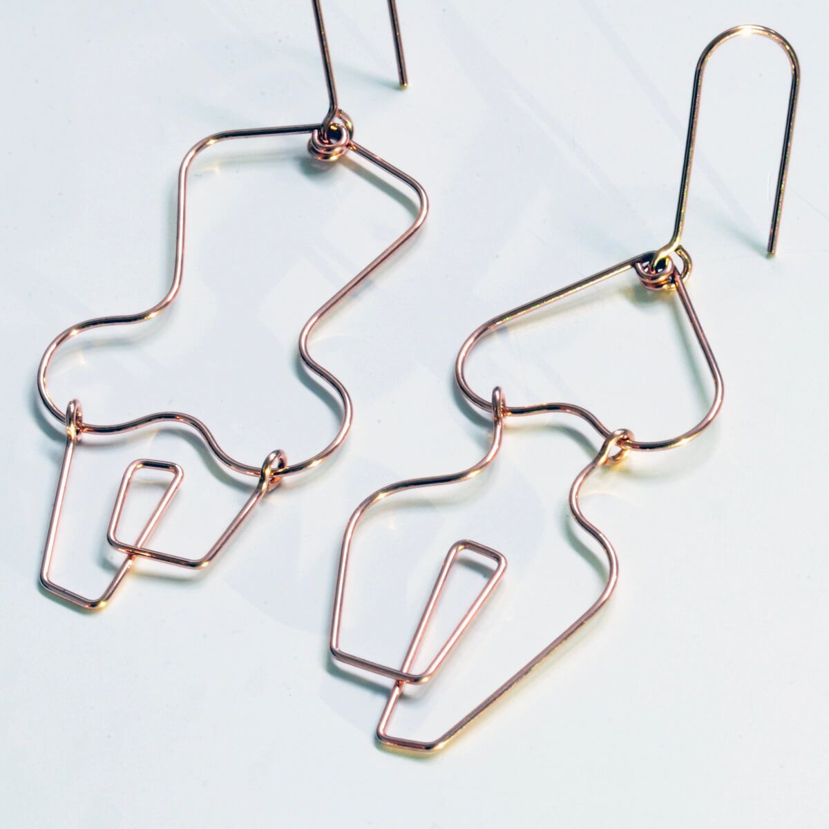 a pair of fine wire earrings in shapes that resemble female bodies