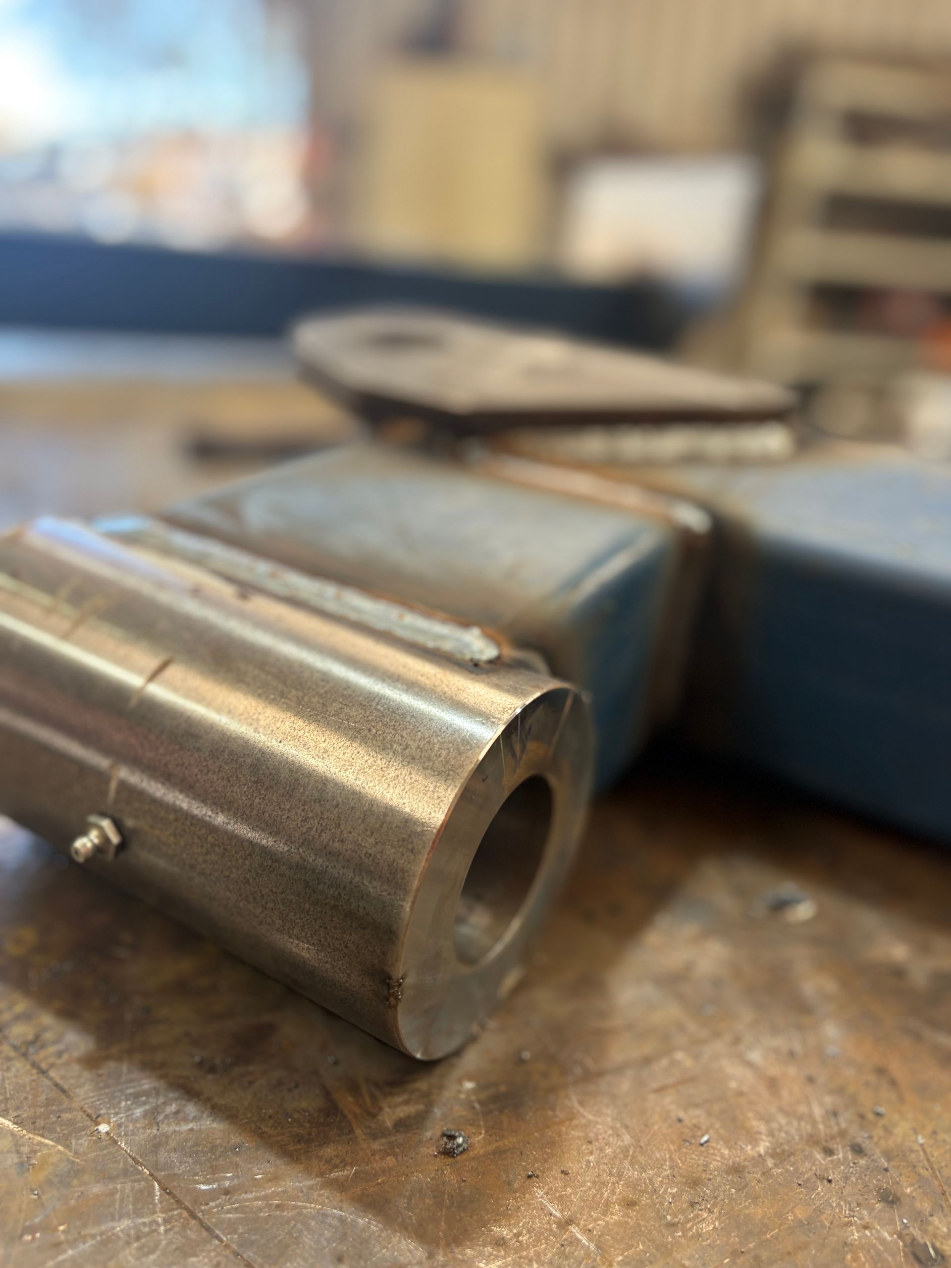 Close-up of a metal shaft with a hole, part of a larger, blue metal structure, likely in a workshop.