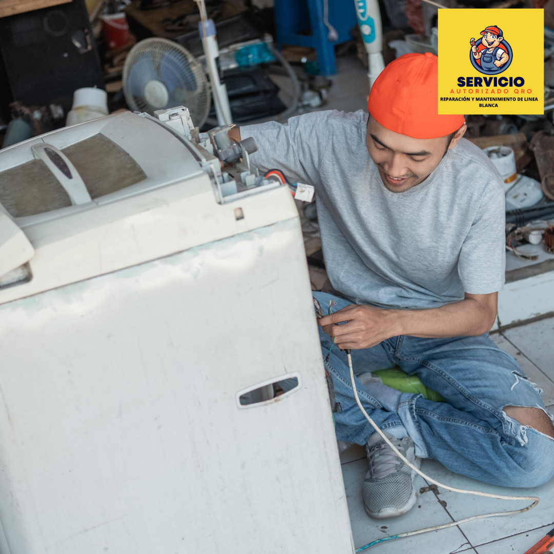 Un hombre está sentado en el suelo arreglando una lavadora.