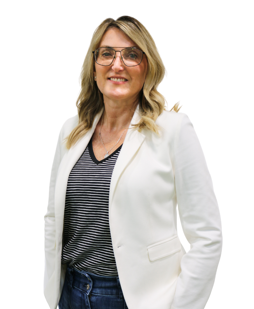 A woman wearing glasses and a white jacket is standing with her hands in her pockets.