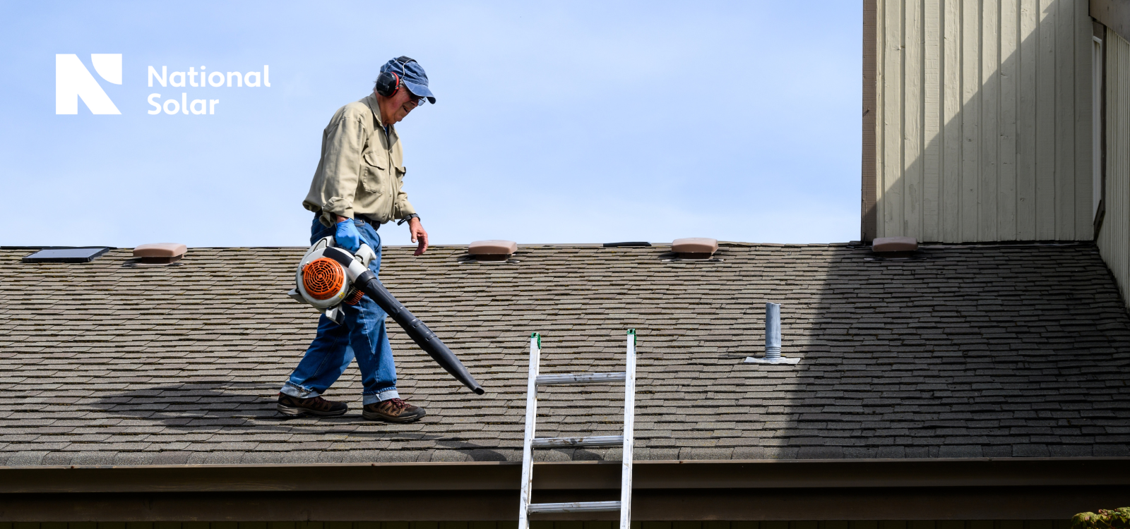 A man standing on a roof with a national solar logo behind him