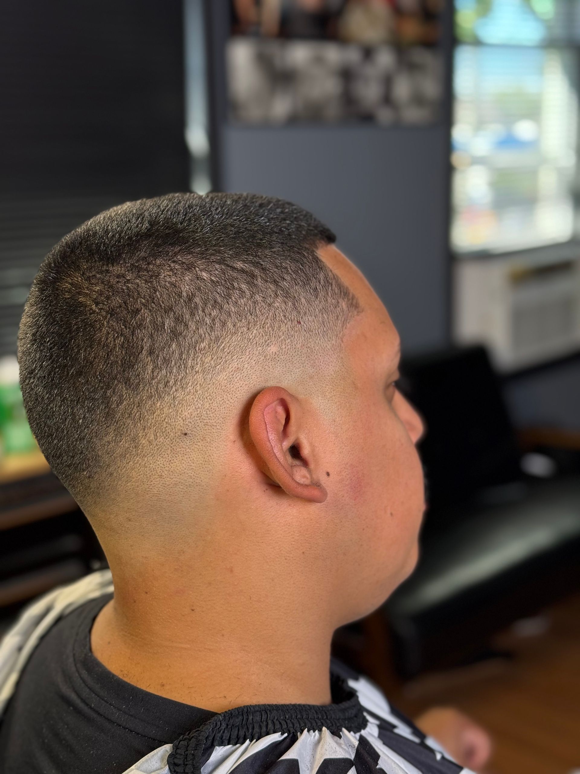 Man with a faded haircut at a barber shop, side profile.