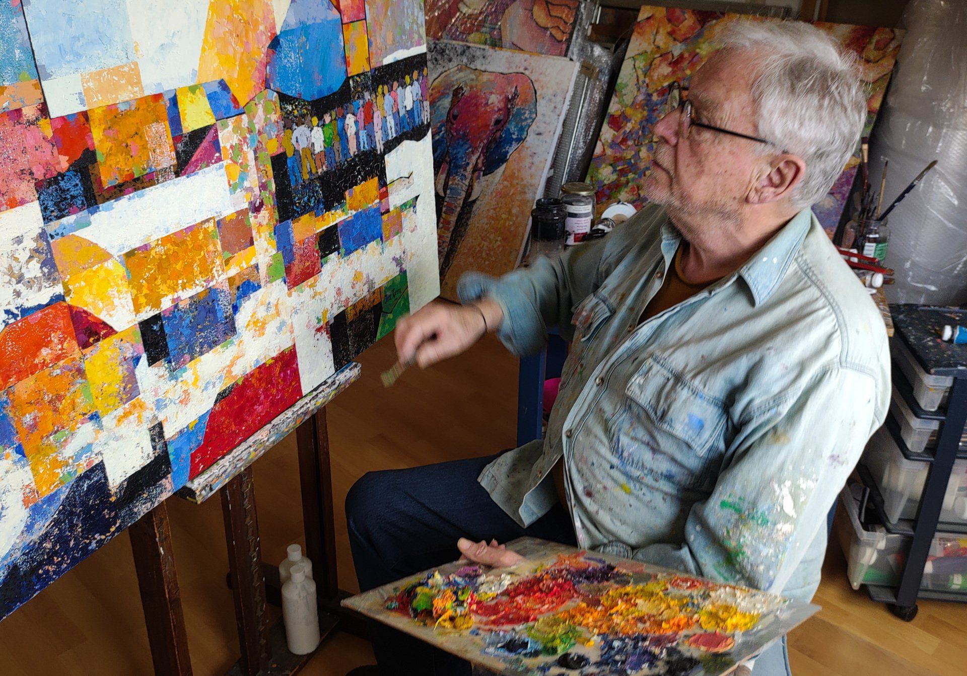 Een man schildert een schilderij met een palet en een penseel.