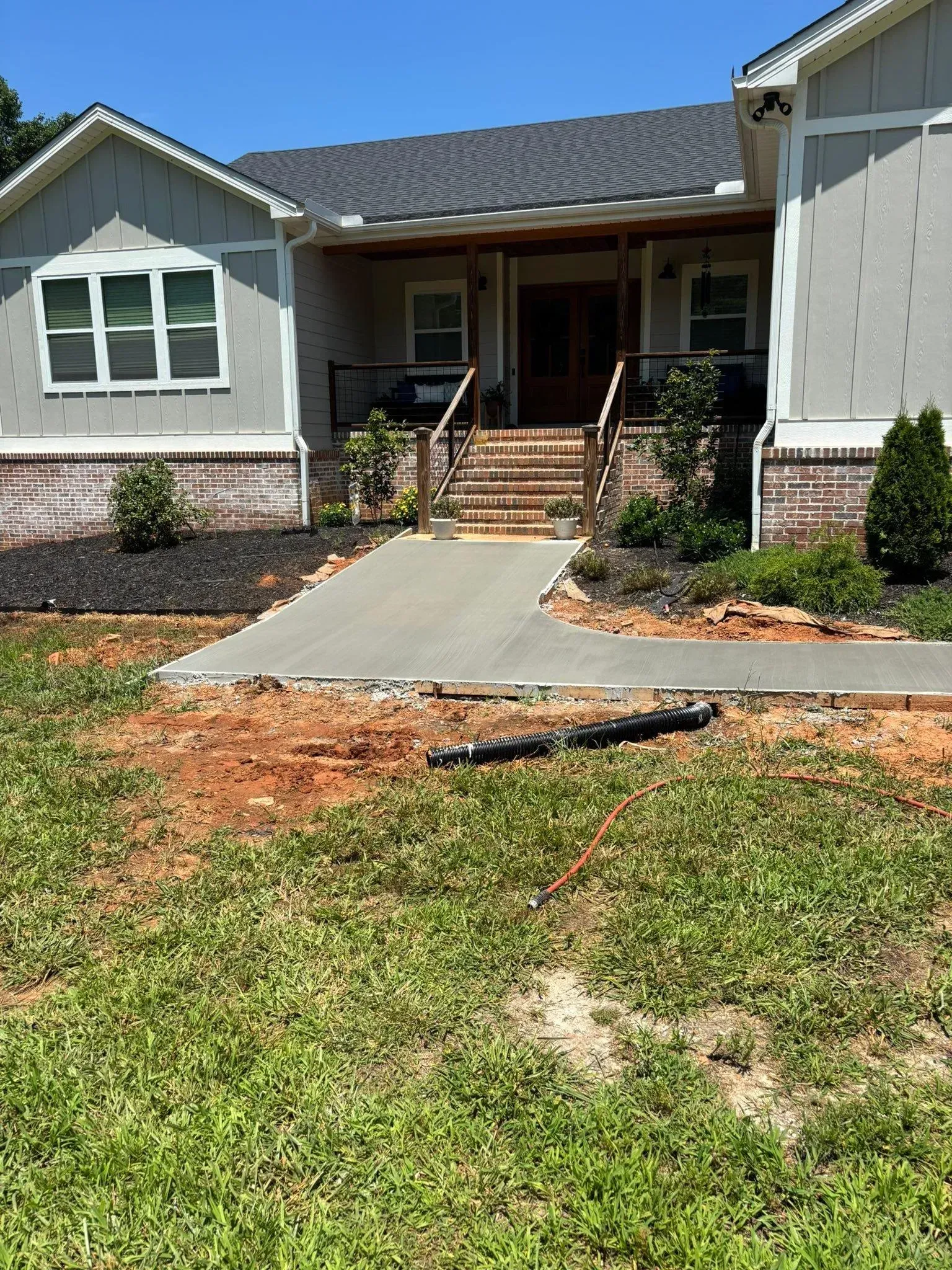 A new concrete walkway leading to a house's front porch. The yard is unfinished.