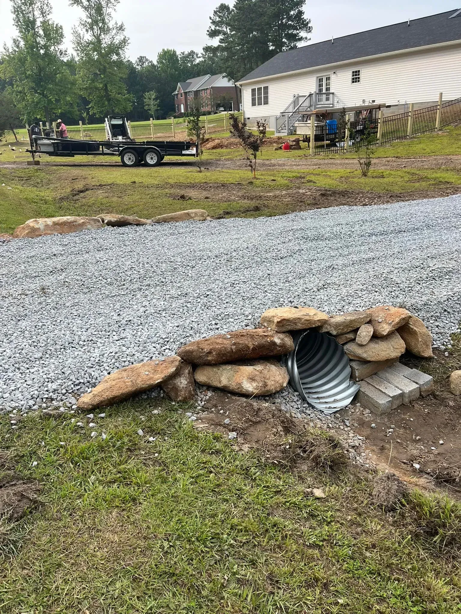 Construction site: a culvert with gravel, rocks, and a nearby truck carrying sod.