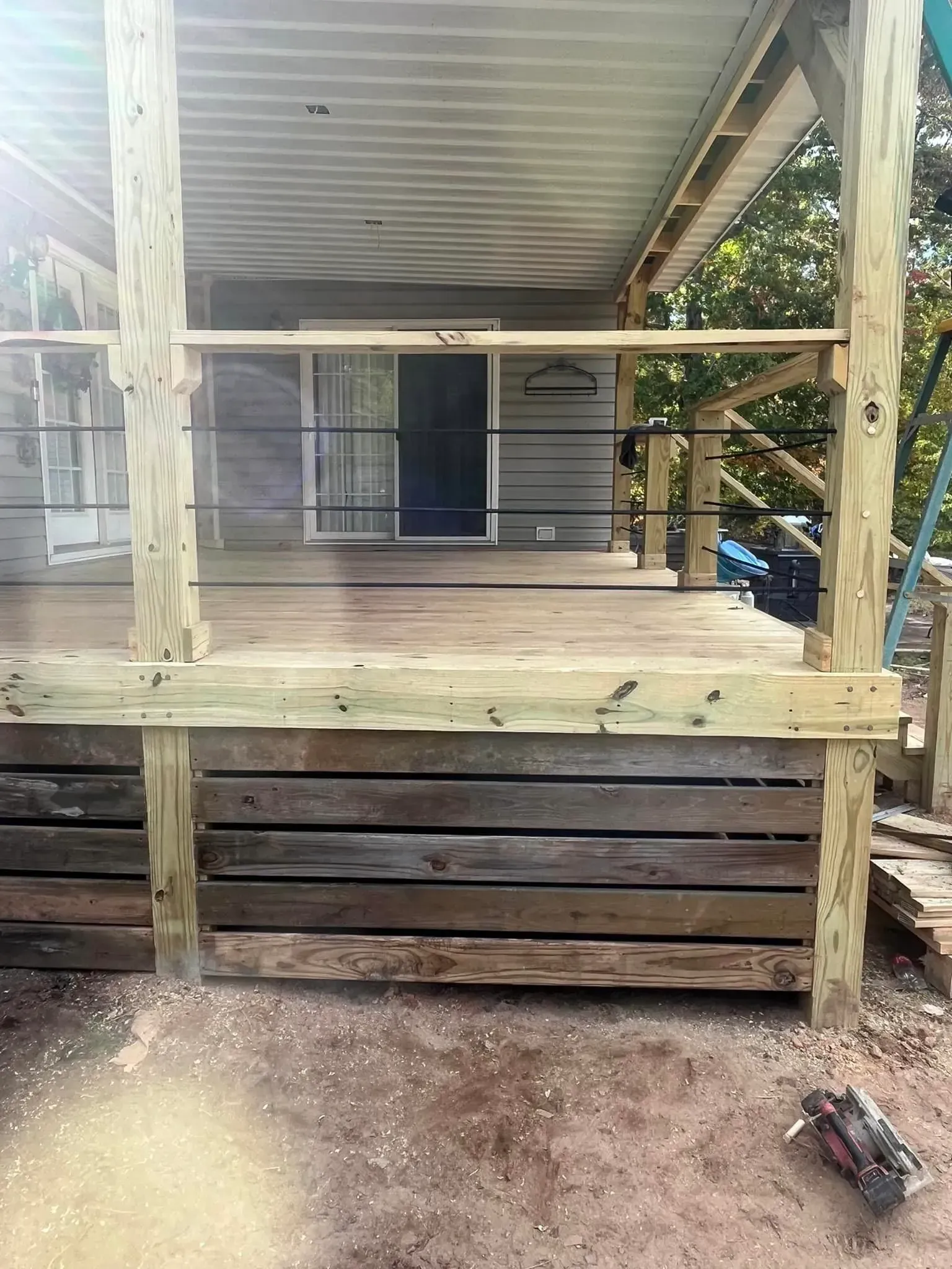 Deck construction: wooden deck with railing and metal cable.