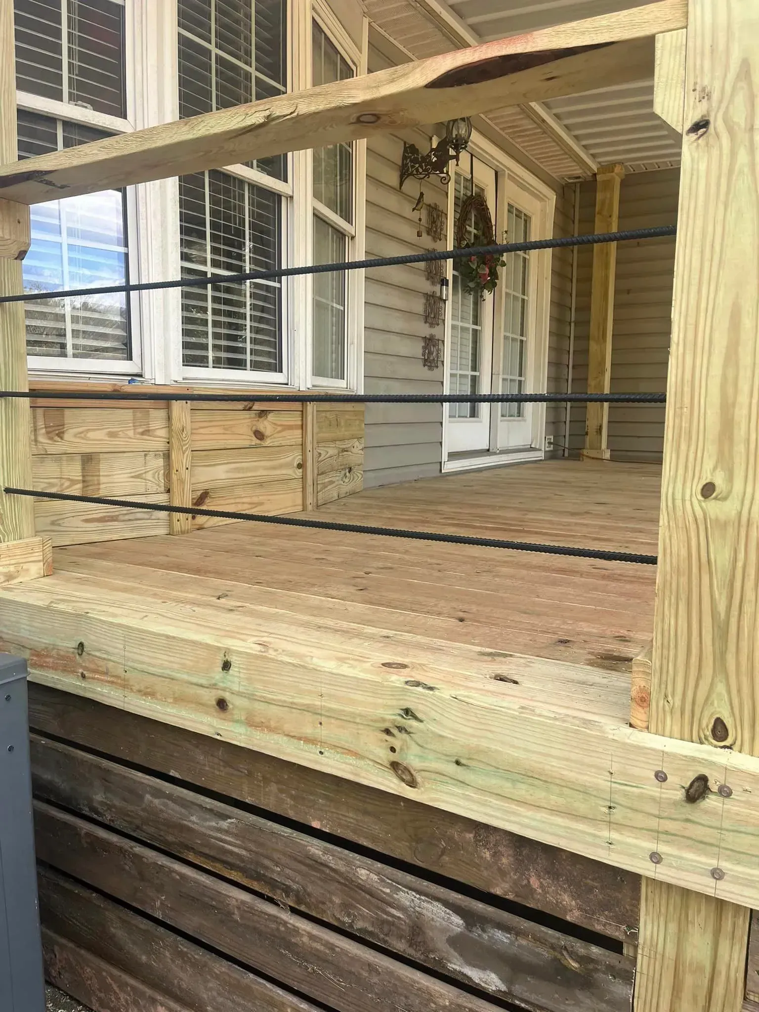 Wooden porch with cable railing, windows, and a door.