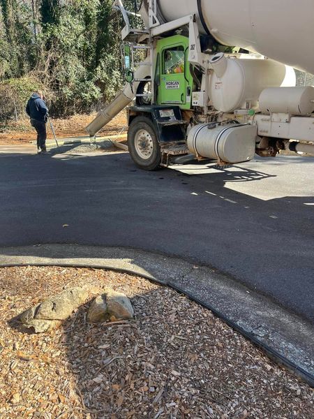 Concrete truck on asphalt road, pouring concrete. Person standing nearby.