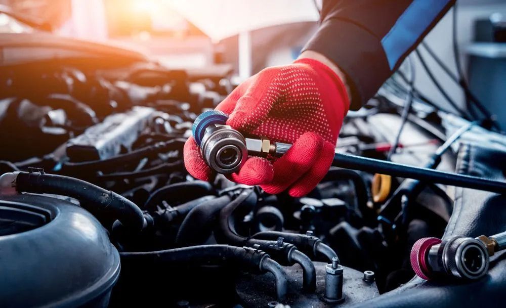 Mechanic's Gloved Hand Holding a Coupling Over a Car Engine, Preparing for Repair Work — Cool Cars NT in Anula, NT