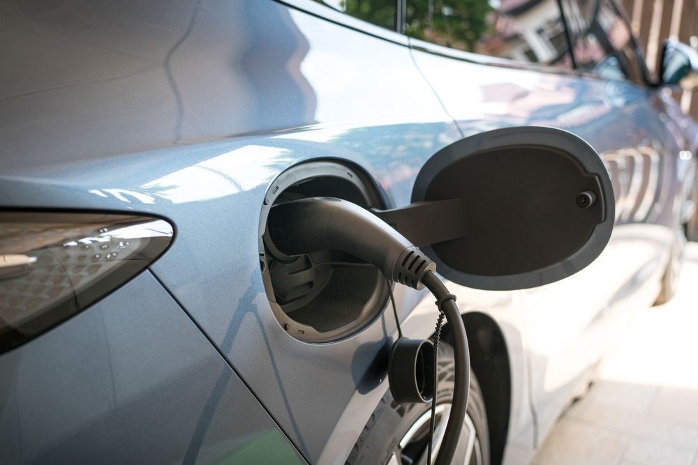 A charging cable connected to the fuel door of a light blue electric car. — Cool Cars NT in Palmerston, NT