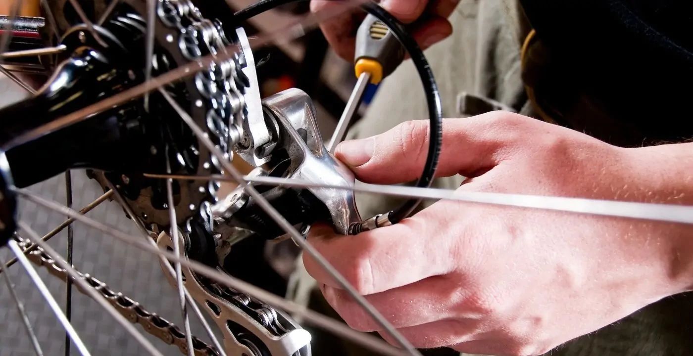 A person is fixing a bicycle with a screwdriver.