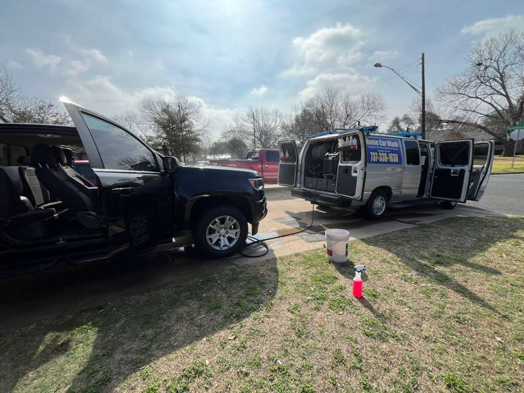 Two black vans parked on grass with side doors open, showing the vehicle interiors outdoors on a sunny day.