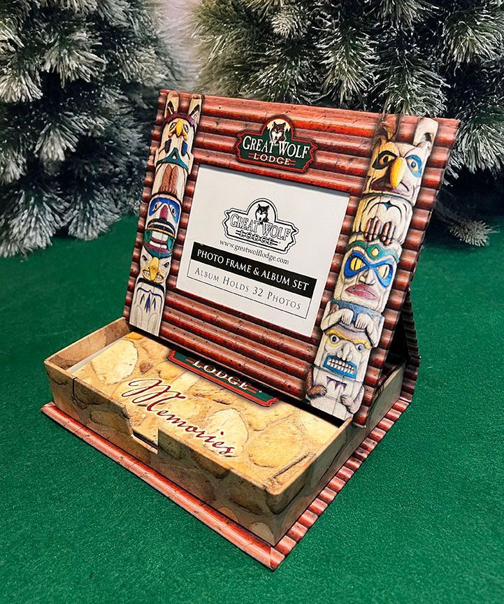 A picture frame is sitting on top of a box of cookies next to a christmas tree.