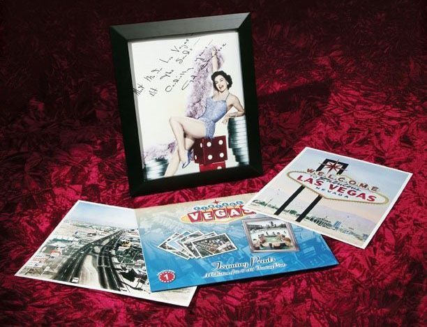 A framed picture of a woman sitting on a pile of dice is surrounded by postcards from las vegas
