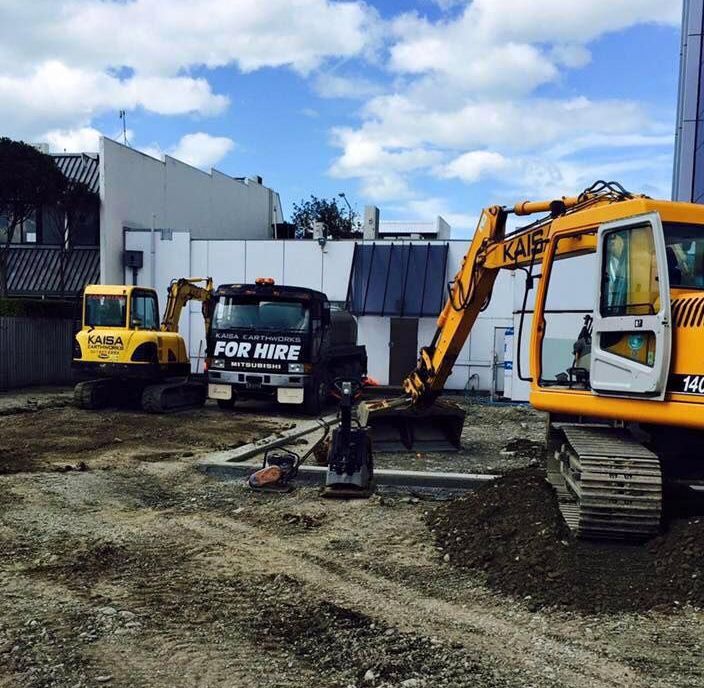 A large orange excavator is sitting in a dirt field.
