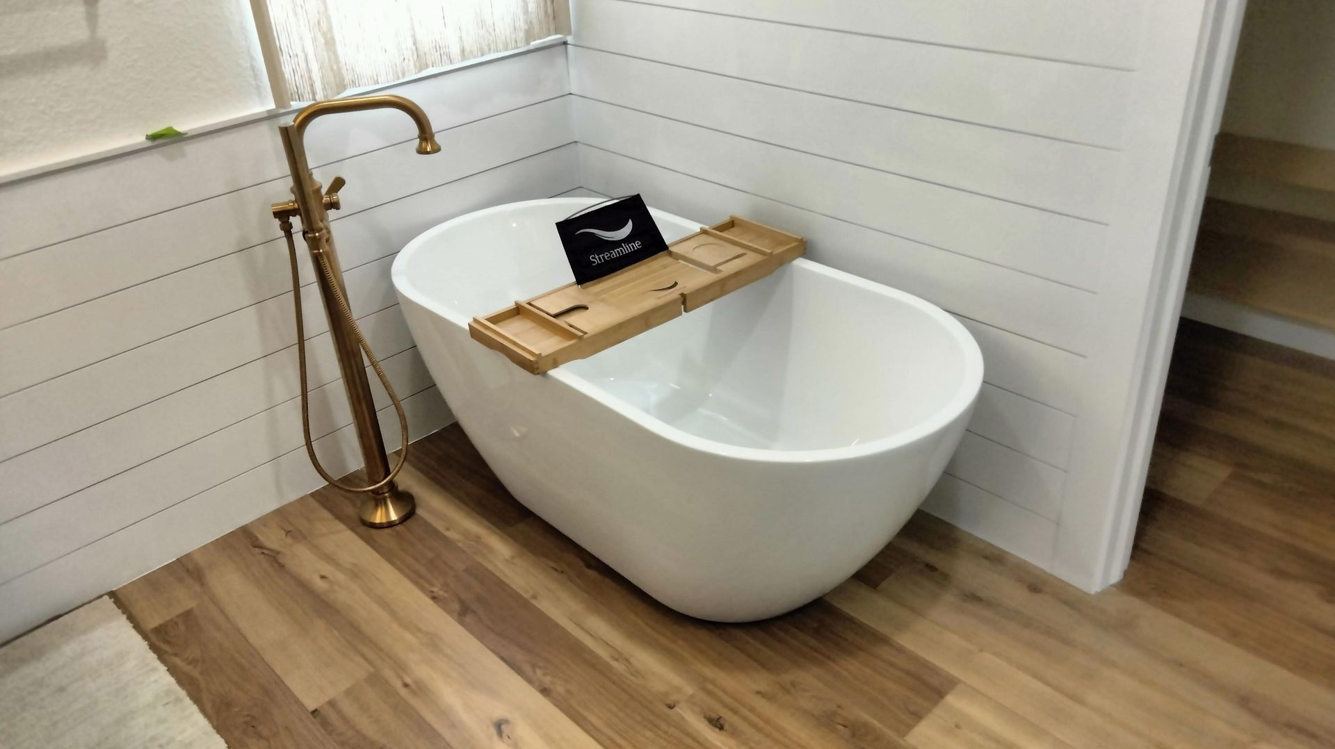 A white bathtub with a wooden tray on top of it in a bathroom.
