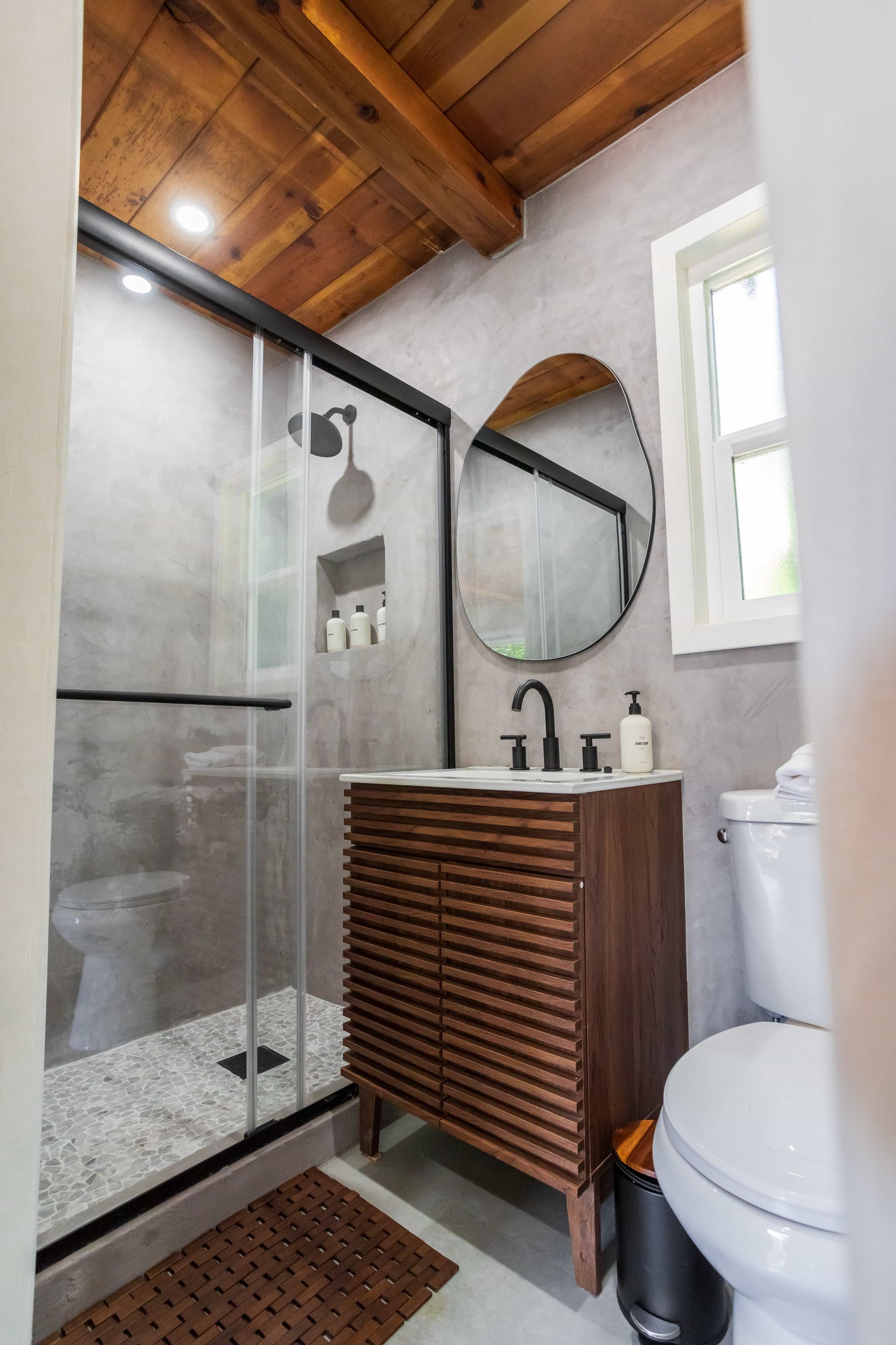 A bathroom with a toilet , sink , shower and mirror.