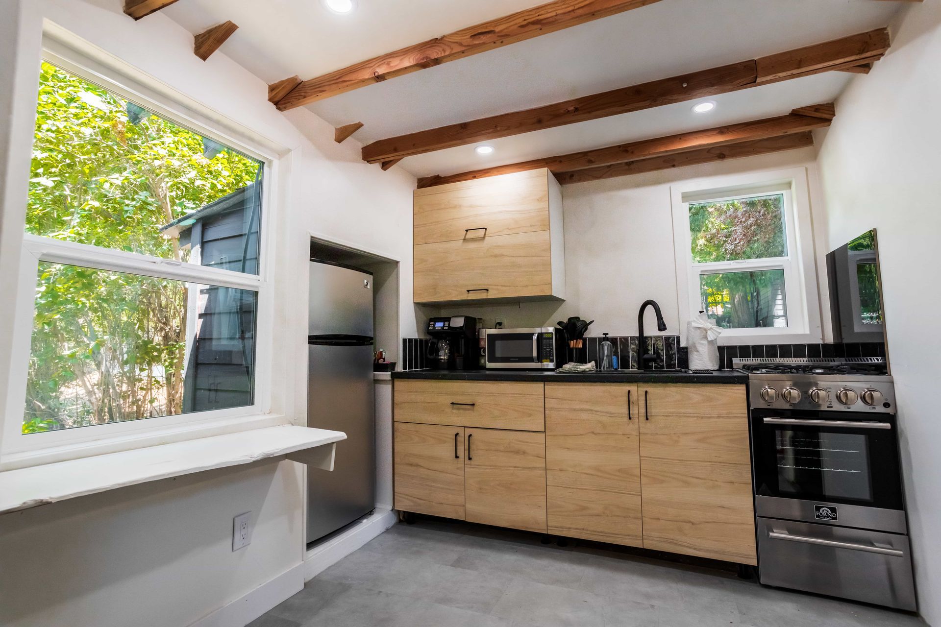 A kitchen with wooden cabinets , stainless steel appliances and a window.