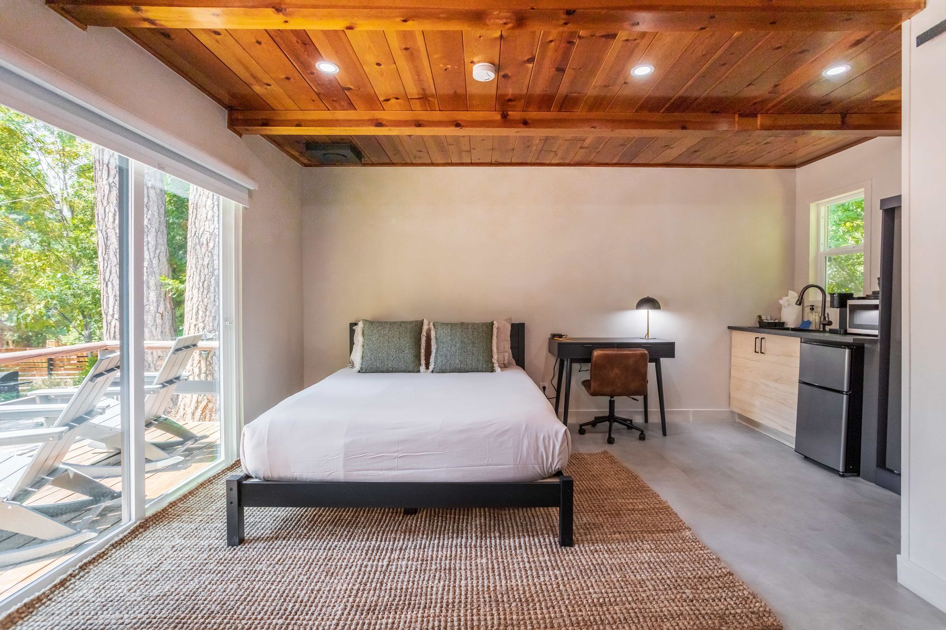 A bedroom with a bed , desk , and sliding glass doors.