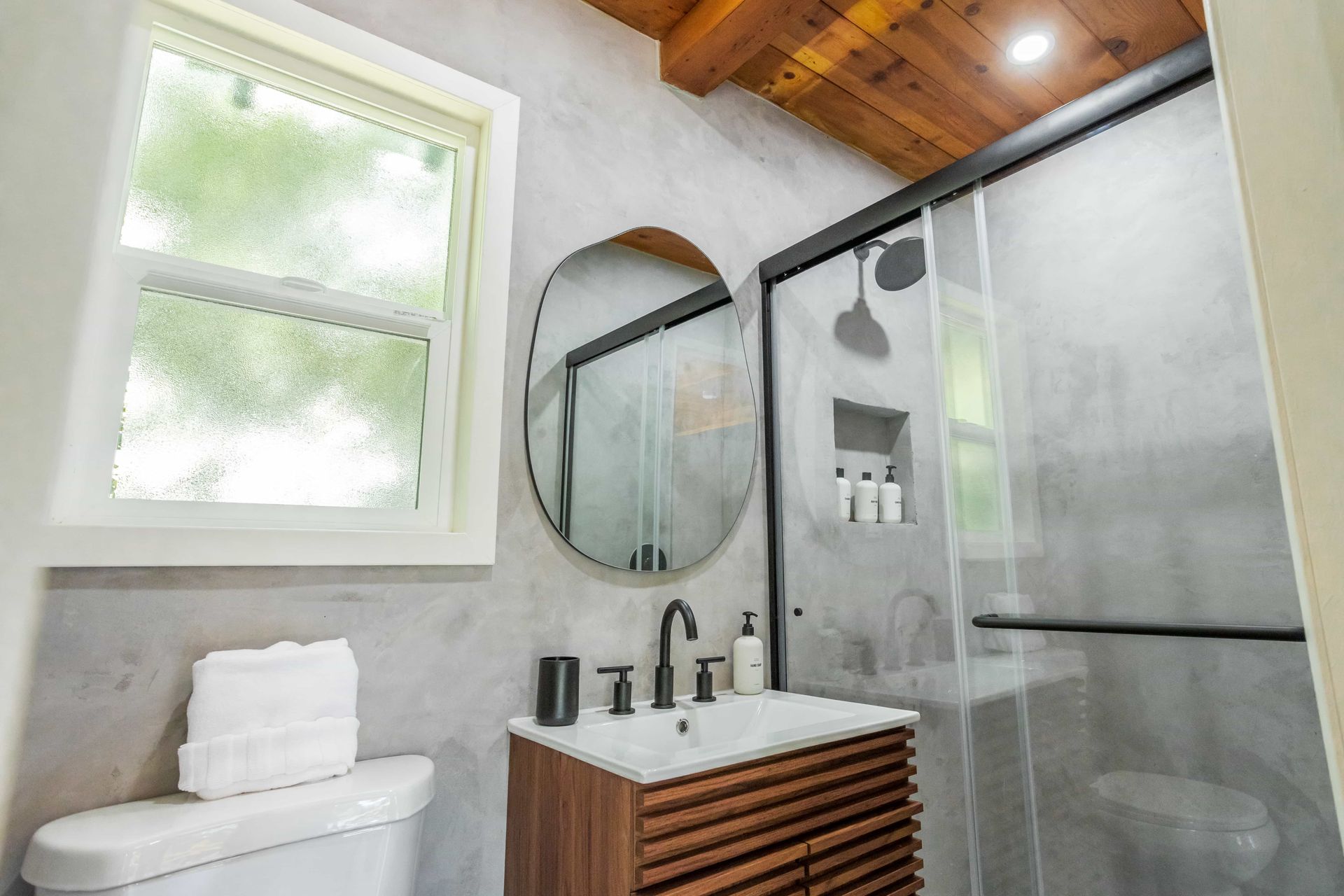 A bathroom with a toilet , sink , mirror and shower.