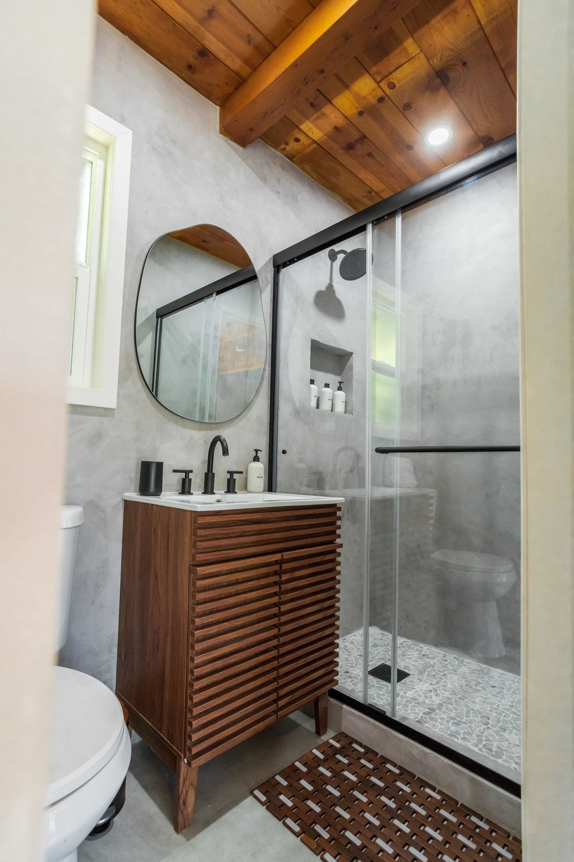 A bathroom with a toilet , sink , mirror and shower.