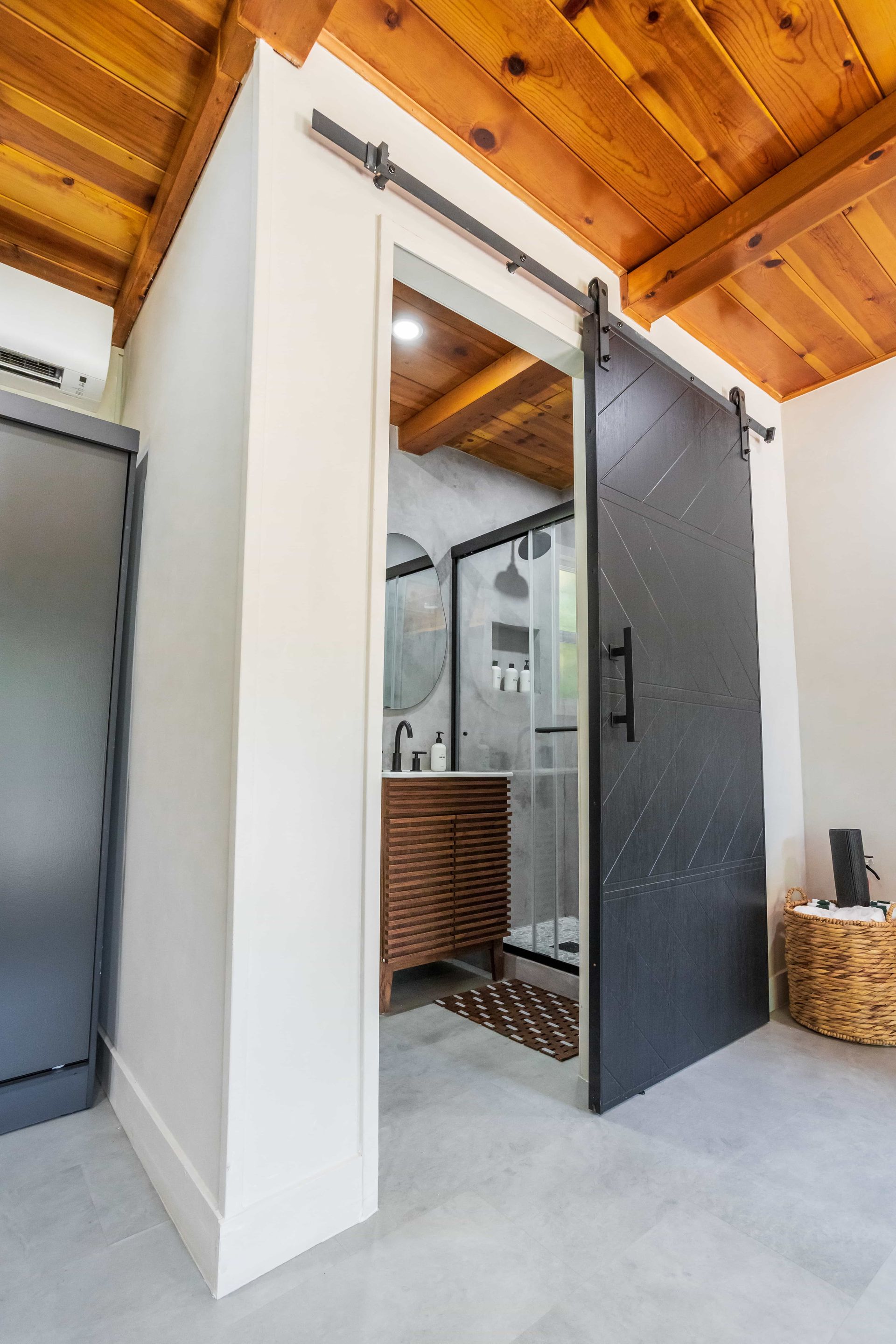 A bathroom with a sliding barn door and a wooden ceiling.