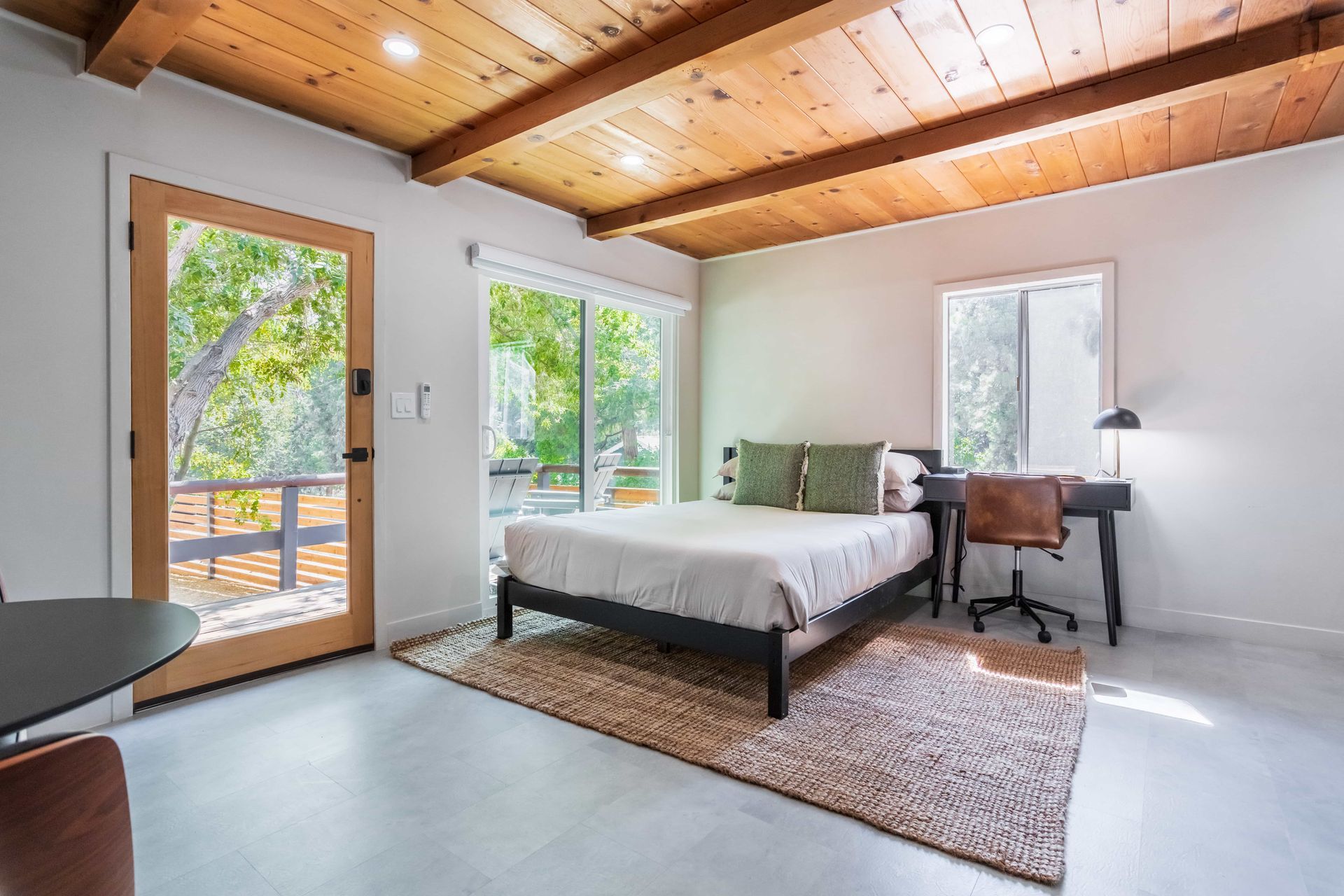 A bedroom with a bed , desk , chair and sliding glass doors.