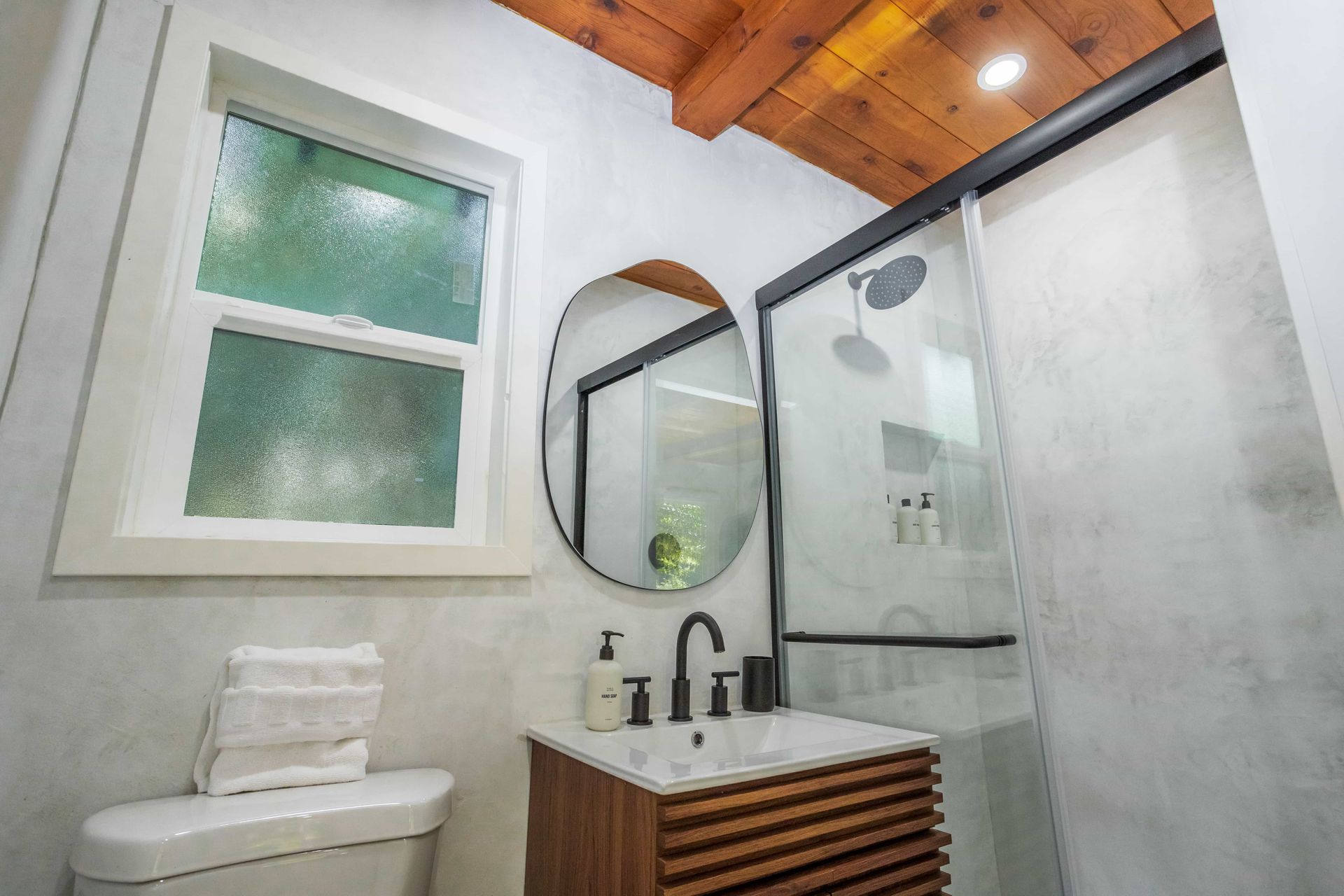 A bathroom with a toilet , sink , mirror and shower.