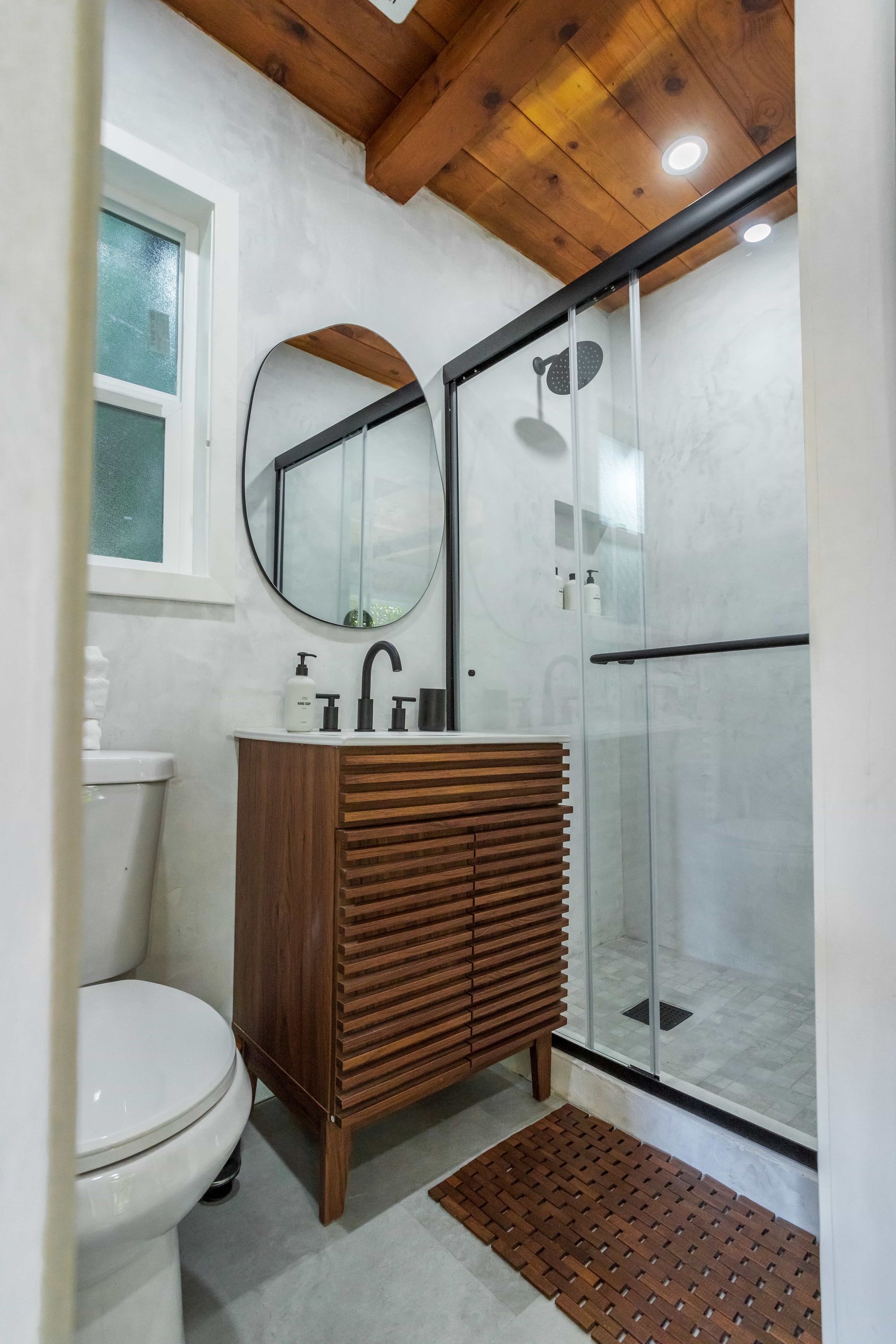 A bathroom with a toilet , sink , mirror and shower.