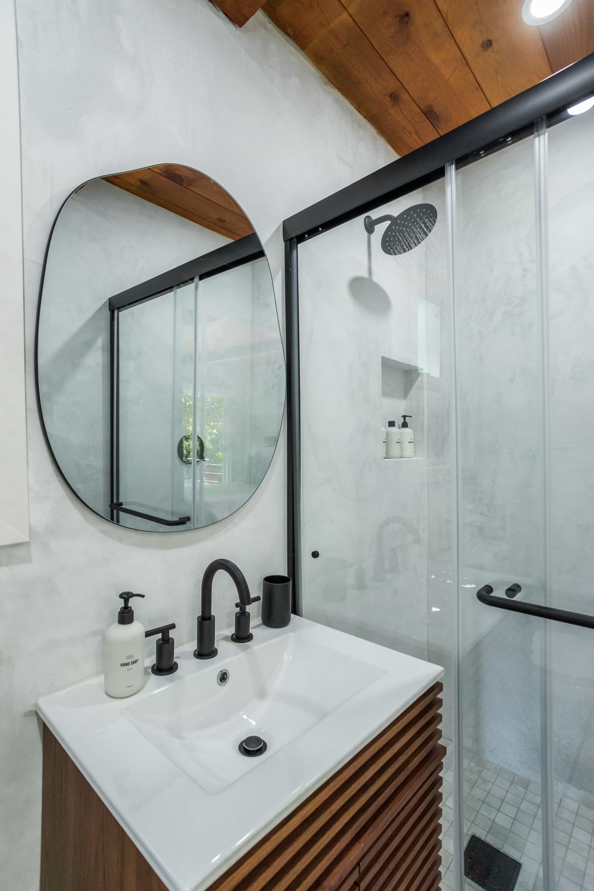 A bathroom with a sink , mirror and shower.