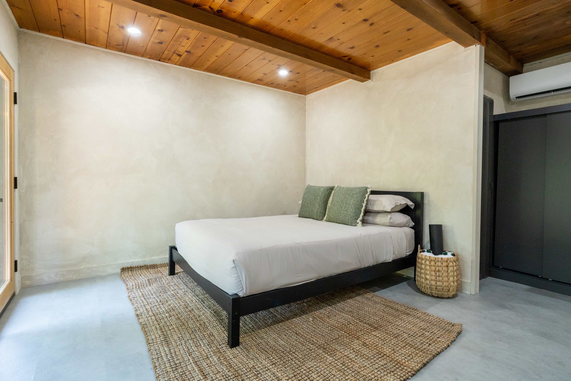 A bedroom with a bed , rug , and wooden ceiling.