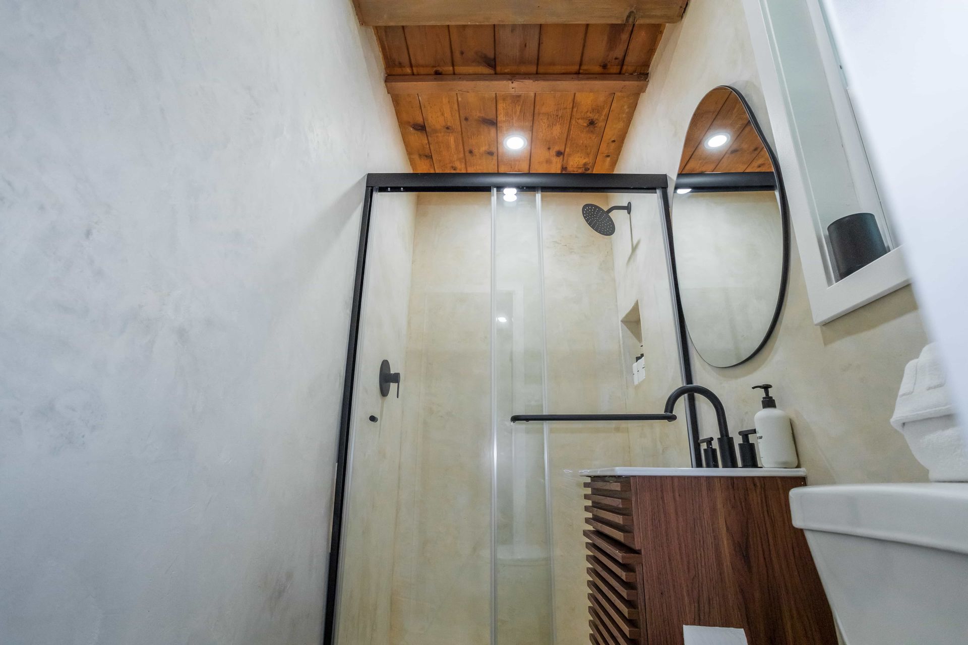 A bathroom with a toilet , sink , shower and mirror.