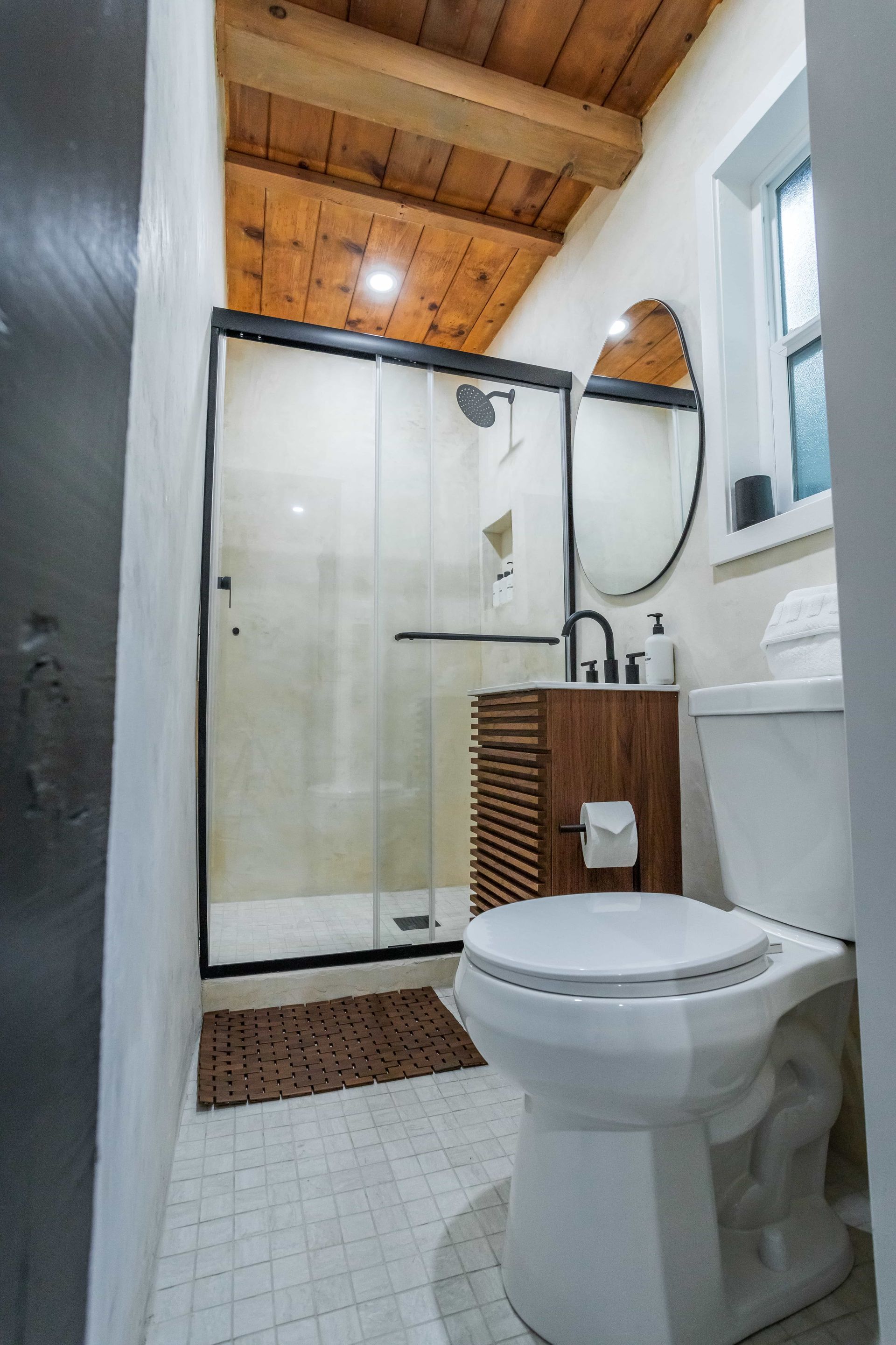 A bathroom with a toilet , sink , shower and mirror.