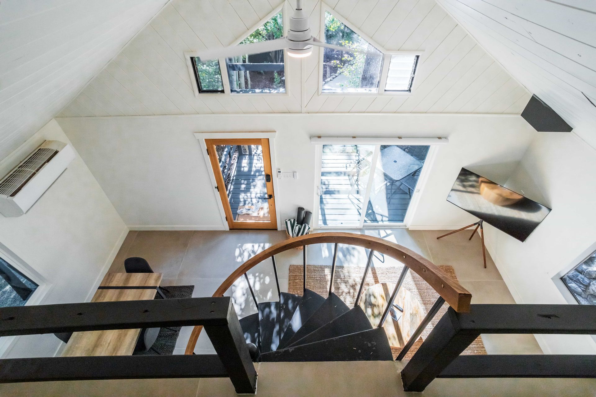 An aerial view of a living room with a spiral staircase leading to the second floor.